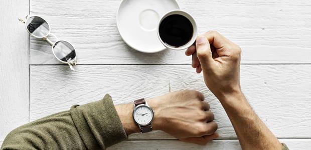 A man sitting at a table and looking at his watch