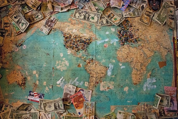 Various global currencies spread across a world map.