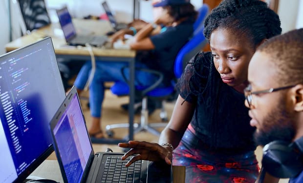 A couple of people working together on code at a laptop