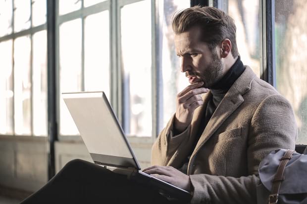 A man staring confusedly at his laptop