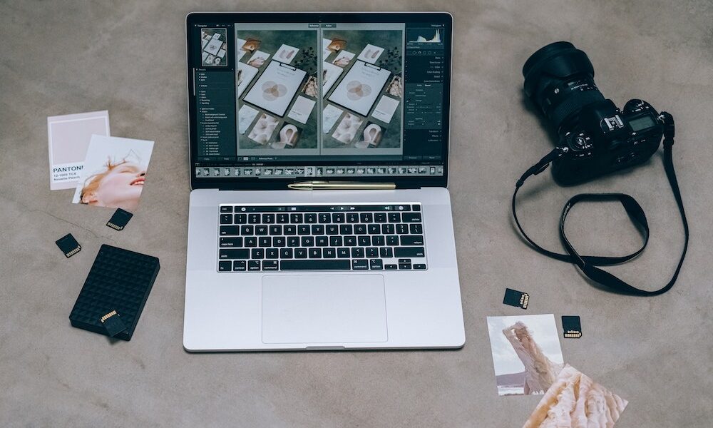 A MacBook with editing software, a camera, and color charts.